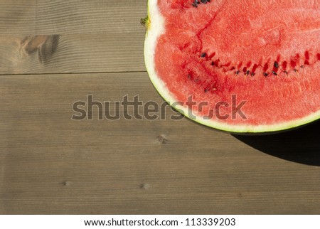 half of water melon on wooden, mediterranean garden background