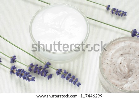 facial cream and mask, blue lavender flowers on white textile background