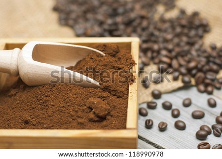 coffee beans, ground coffee with wooden spoon on rusty wood background