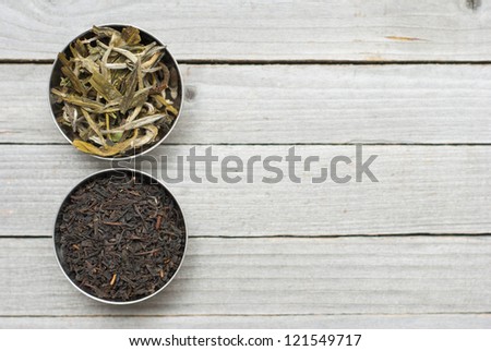 black, green tea leaves, wooden table background