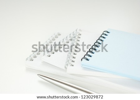 empty notebooks with pen on white office table, focus on pen, shallow depth of field