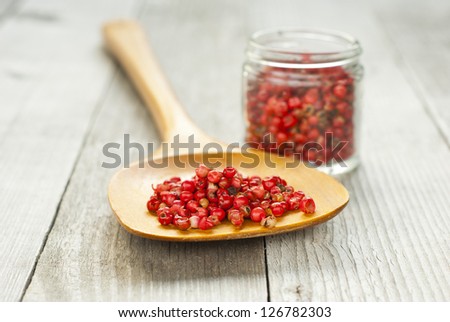 rose pepper on wooden spoon, rustic wood table