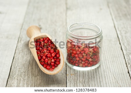 rose pepper on wooden spoon, rustic wood table