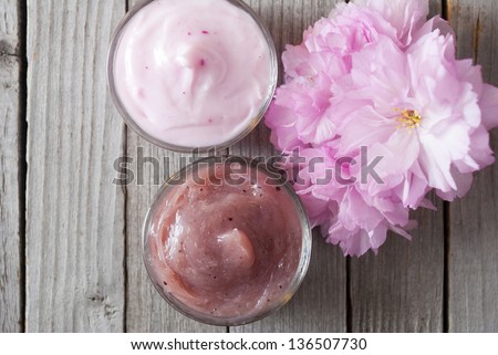 moisturizer cream in glass jar, ornated with japanese cherry blossoms on wooden surface