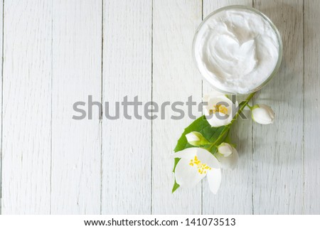facial cream with jasmine blossom on white wooden table