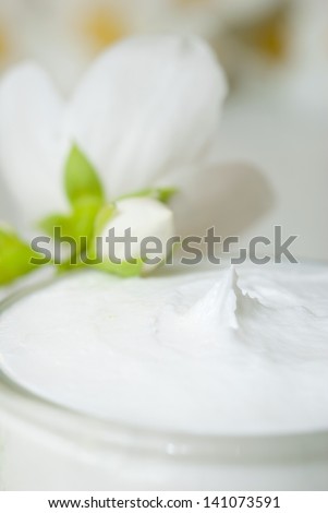 facial cream with jasmine blossom on white wooden table