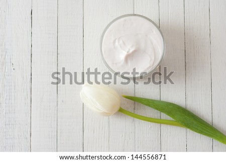 cosmetic cream with tulips on white wooden