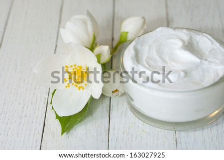 cosmetic cream with jasmine blossom on white wooden table