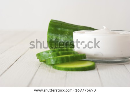 face mask with cucumber slices, white wood background