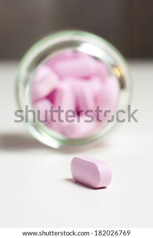 pink vitamin pills in glass jar