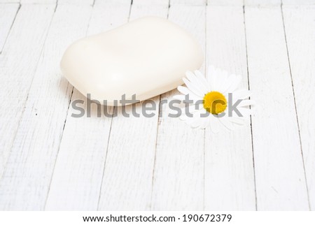 bar of soap with chamomile flower on white wood table