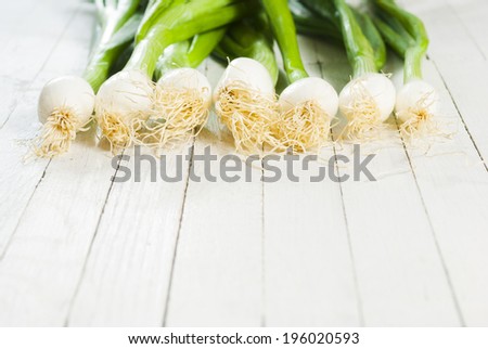 fresh spring onions in a row on white wooden table