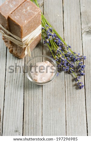 cosmetic cream, soap blocks and lavender flowers on old wood background