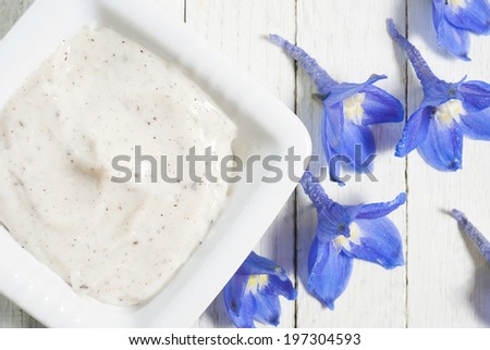 face cream and flowers on white wooden background directly above