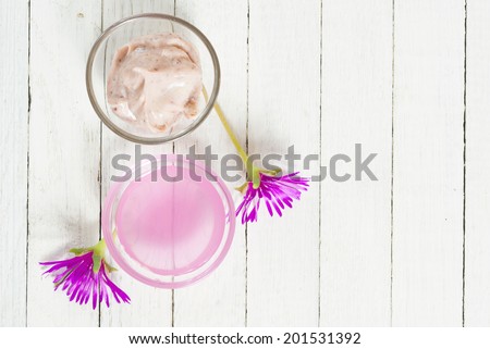 cosmetic creams with purple flowers on white wooden