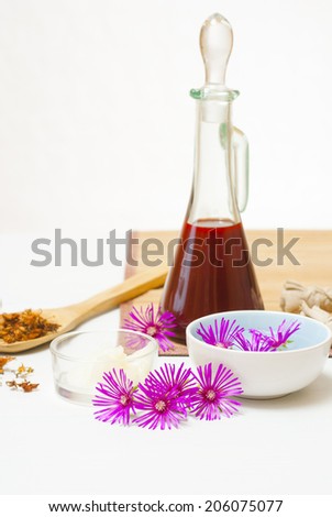 moisturizer with dried St. John's Wort on wooden spoon and floating flowers