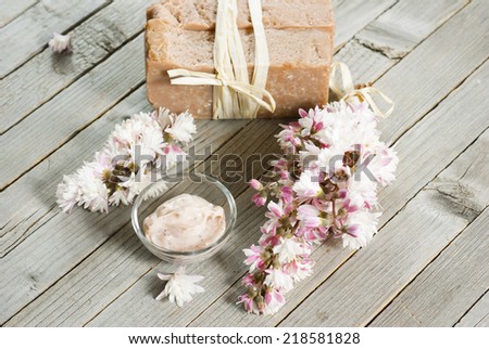 cosmetic cream, soap blocks and flowers on old wood background