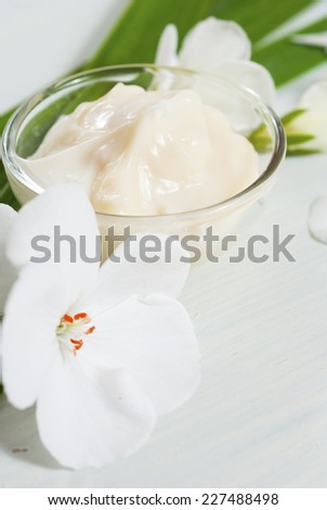 cosmetic cream with white flowers on bright wooden table
