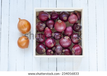 onions in wooden tray, white wood table background