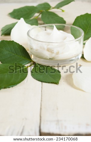 cosmetic cream with white rose petals on bright wooden table