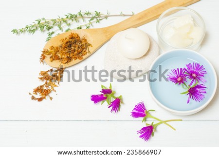 moisturizer with dried St. John's Wort on wooden spoon and floating flowers