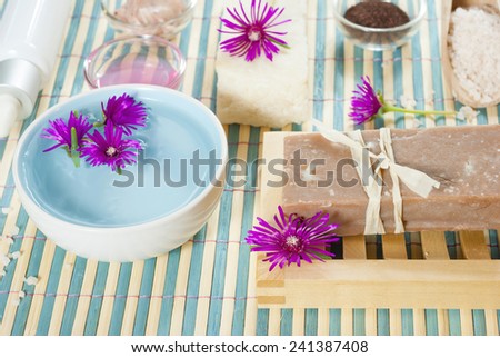 spa setting with lavender soap and floating flowers on bamboo