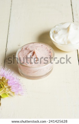 hand and face cream with stone crop flowers on bright, rusty wooden