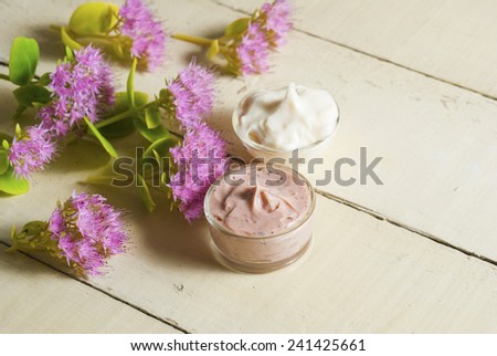 hand and face cream with stone crop flowers on bright, rusty wooden