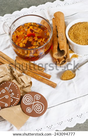 fruit tea with gingerbread cookies, cinnamon rolls, brown sugar and lemon on old fashioned lace cover, rusty wood table