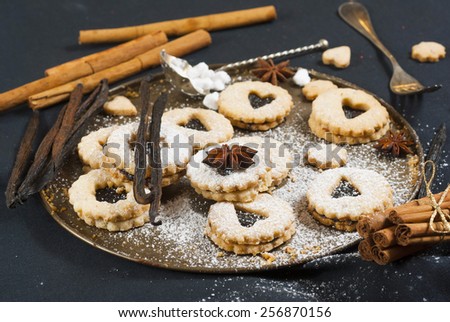 linzer cookies with vanilla beans and cinnamon sticks on black canvas background