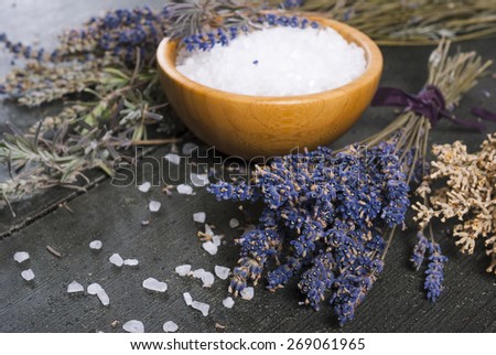 bath salt in bamboo bowl and dried lavender flowers on old black wood table