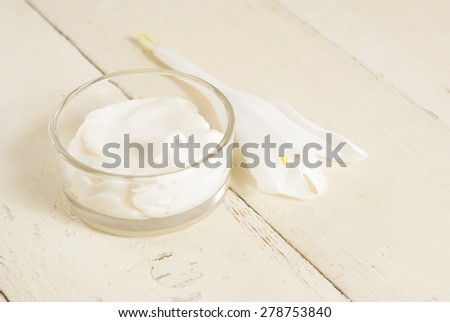 facial cleanser cream with white flower on rusty wooden table