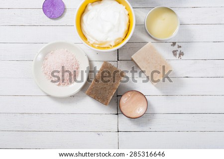 different bath salts,  makeup base, powder compact, soaps on white wooden background