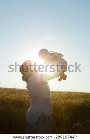mother holding her baby on a wheat filed