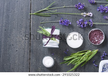 different cosmetic creams, soap with fresh lavender flowers on black wooden texture