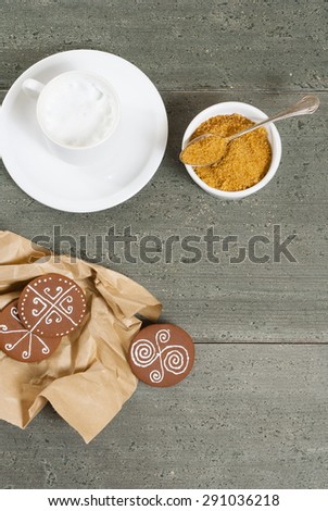 milk coffee with paper wrapped gingerbread cakes and brown sugar on rusty wooden