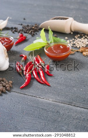 fresh and dried chili fruits, peppercorn, sauce and garlic, bay leaves on old black wooden table background