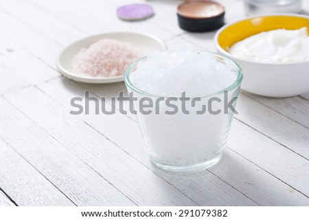 different bath salts, bees wax , makeup base, powder compact, soaps and cosmetic creams on white wooden background
