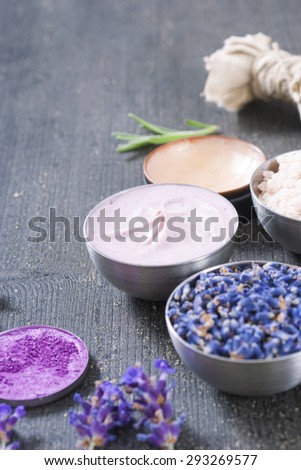 beauty product samples with fresh purple and blue dried lavenders, bath salts on dark wood table background