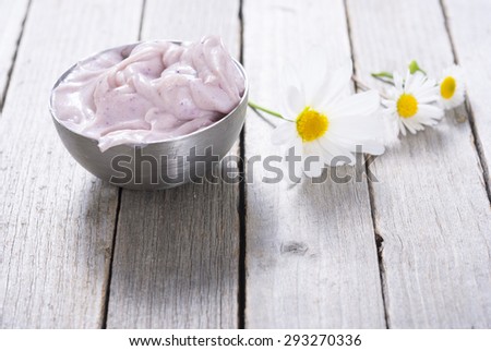 pink cosmetic cream and white herbal flowers on old rusty wooden table background