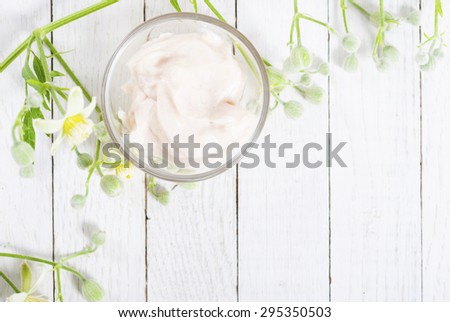 cosmetic cream and white wildflower on bright wood table background