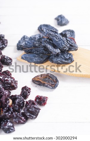 dried cherry, raisin and plum fruits on white wood