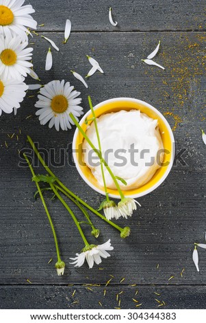 cosmetic cream and white flowers on black wooden table background