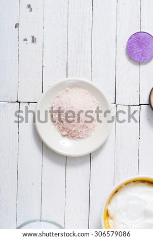 different bath salts , makeup base, powder compact, soaps and cosmetic creams on white wooden background