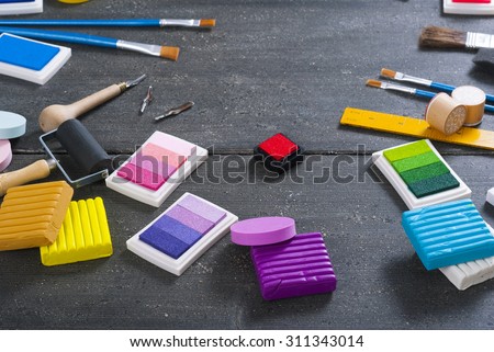 ink pads, plasticine blocks, brushes, paint roller and carving cutters on black wood table