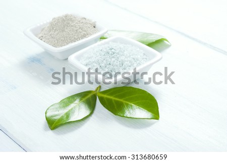 cosmetic clay and bath salt on white wooden table