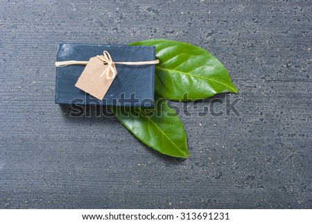 charcoal soap and herbal leaves on black wooden