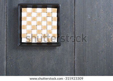 brown and white sugar nubs on black square plate, wood table