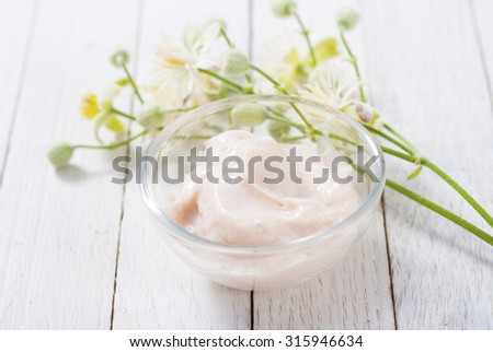 cosmetic cream and white wildflower on bright wood table background
