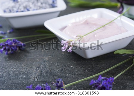 moisturizer cream, soap and bath salt with fresh lavender flowers on black wood background